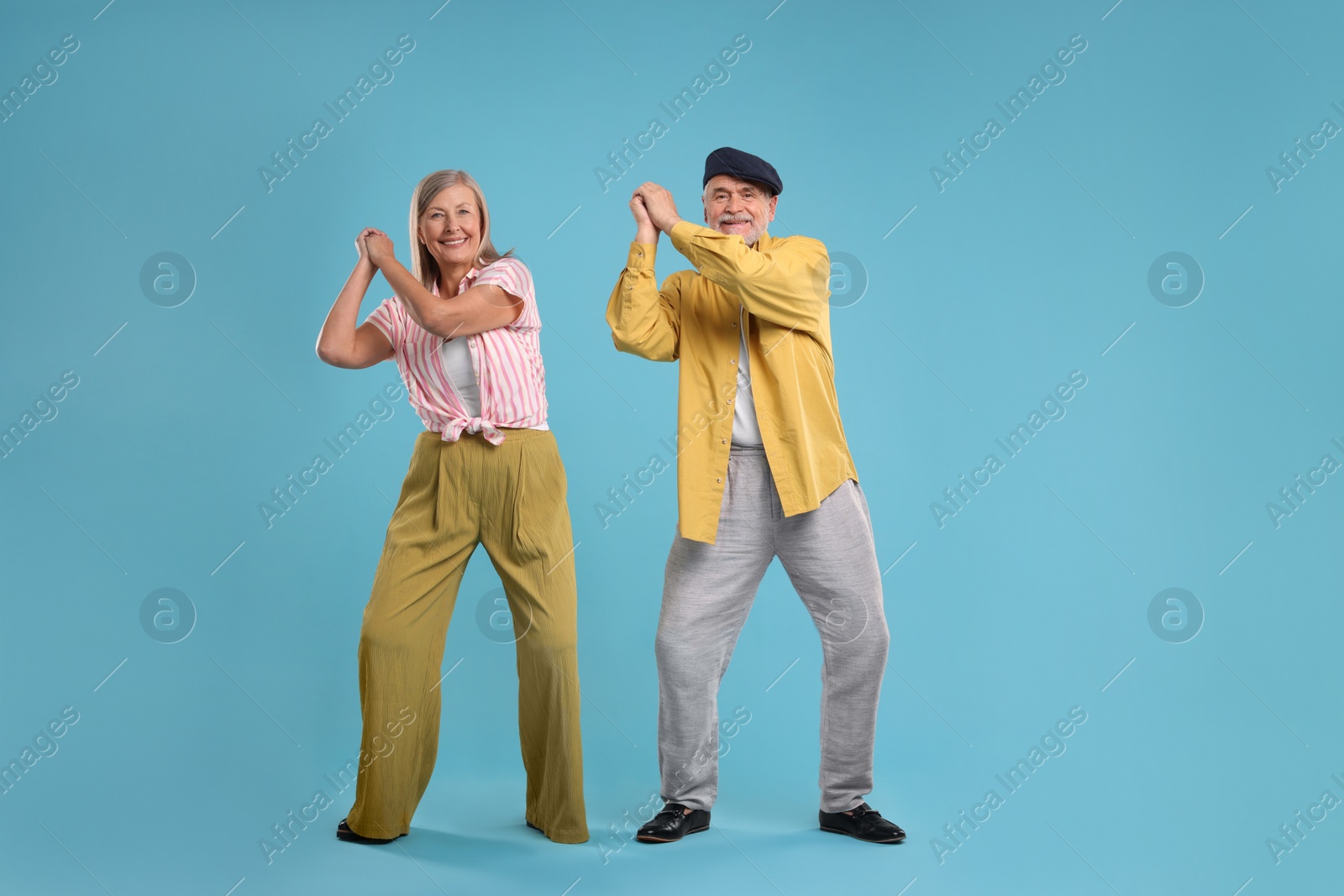 Photo of Senior couple dancing together on light blue background