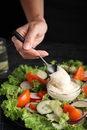 Photo of Woman dressing delicious vegetable salad with mayonnaise at table, closeup