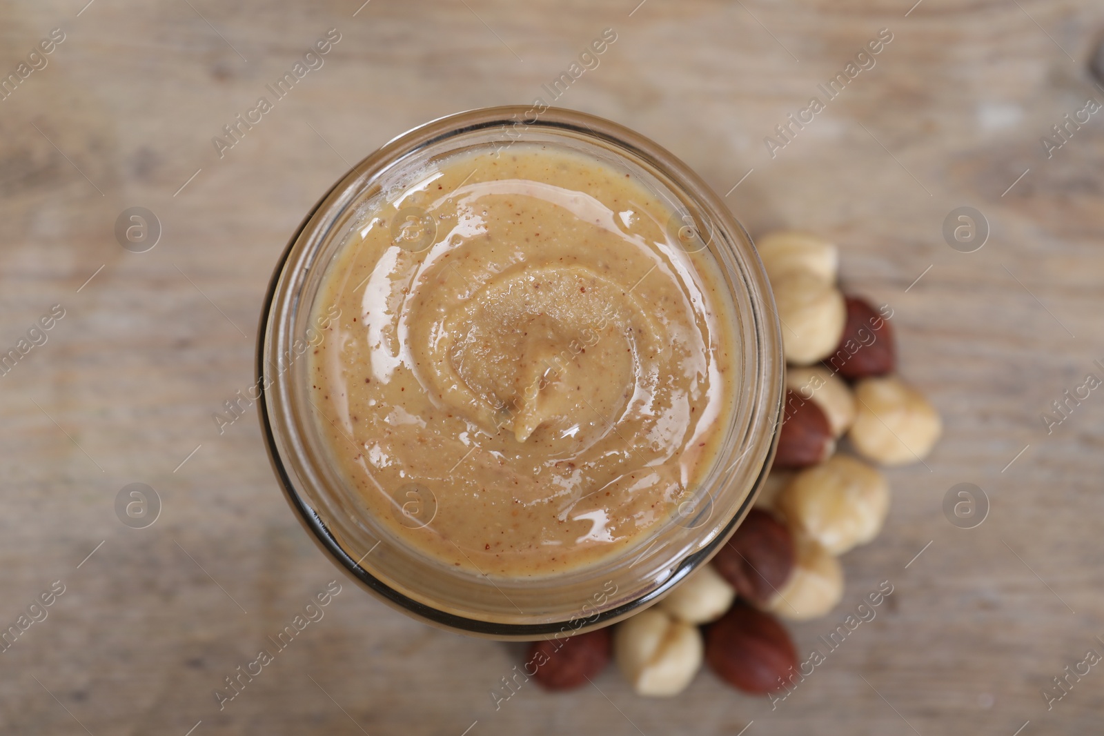 Photo of Tasty hazelnut nut paste in jar on table, top view