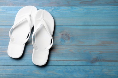 Photo of Stylish beach flip flops on blue wooden background, flat lay. Space for text