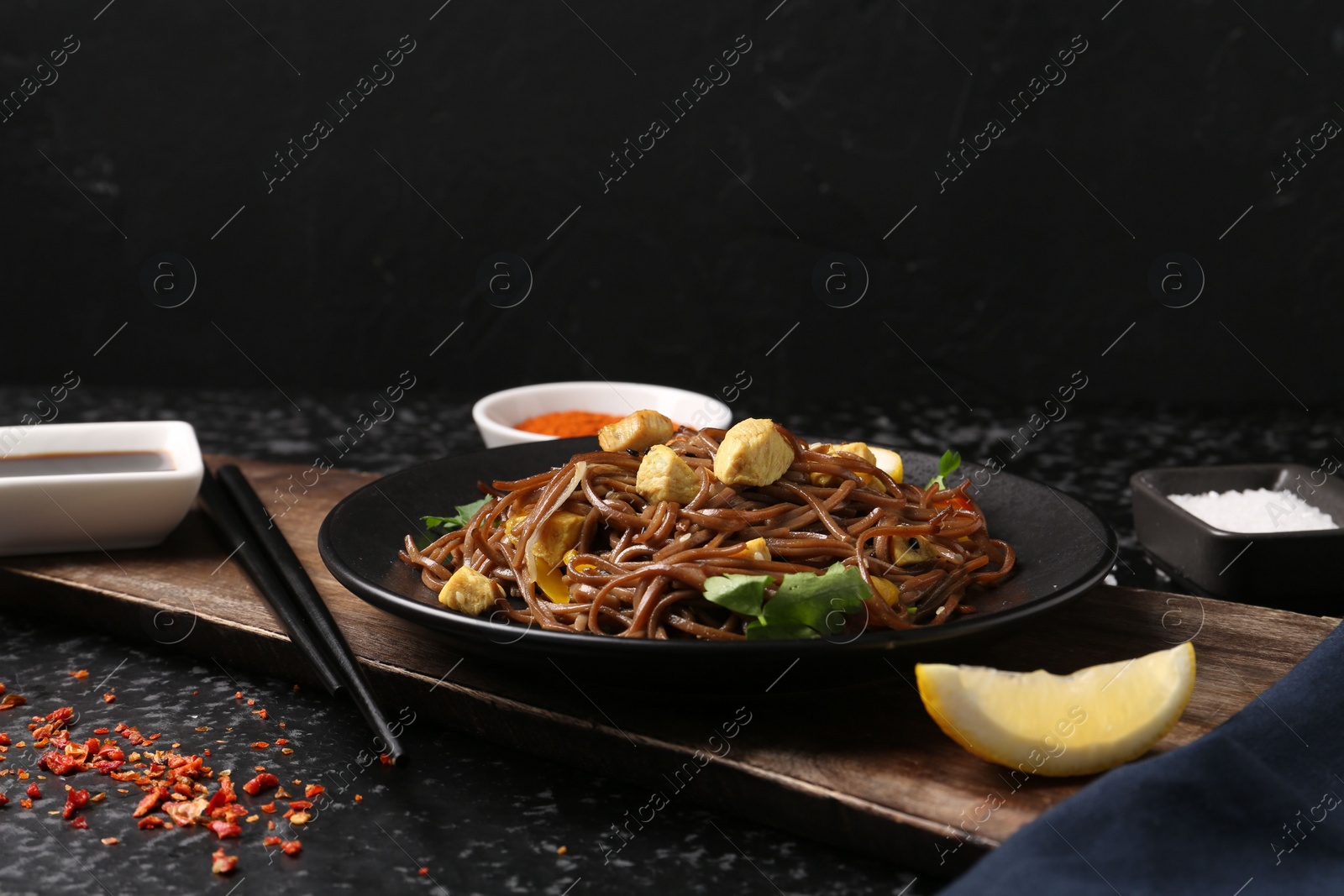 Photo of Stir-fry. Tasty noodles with vegetables and meat served on dark textured table