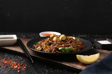 Stir-fry. Tasty noodles with vegetables and meat served on dark textured table