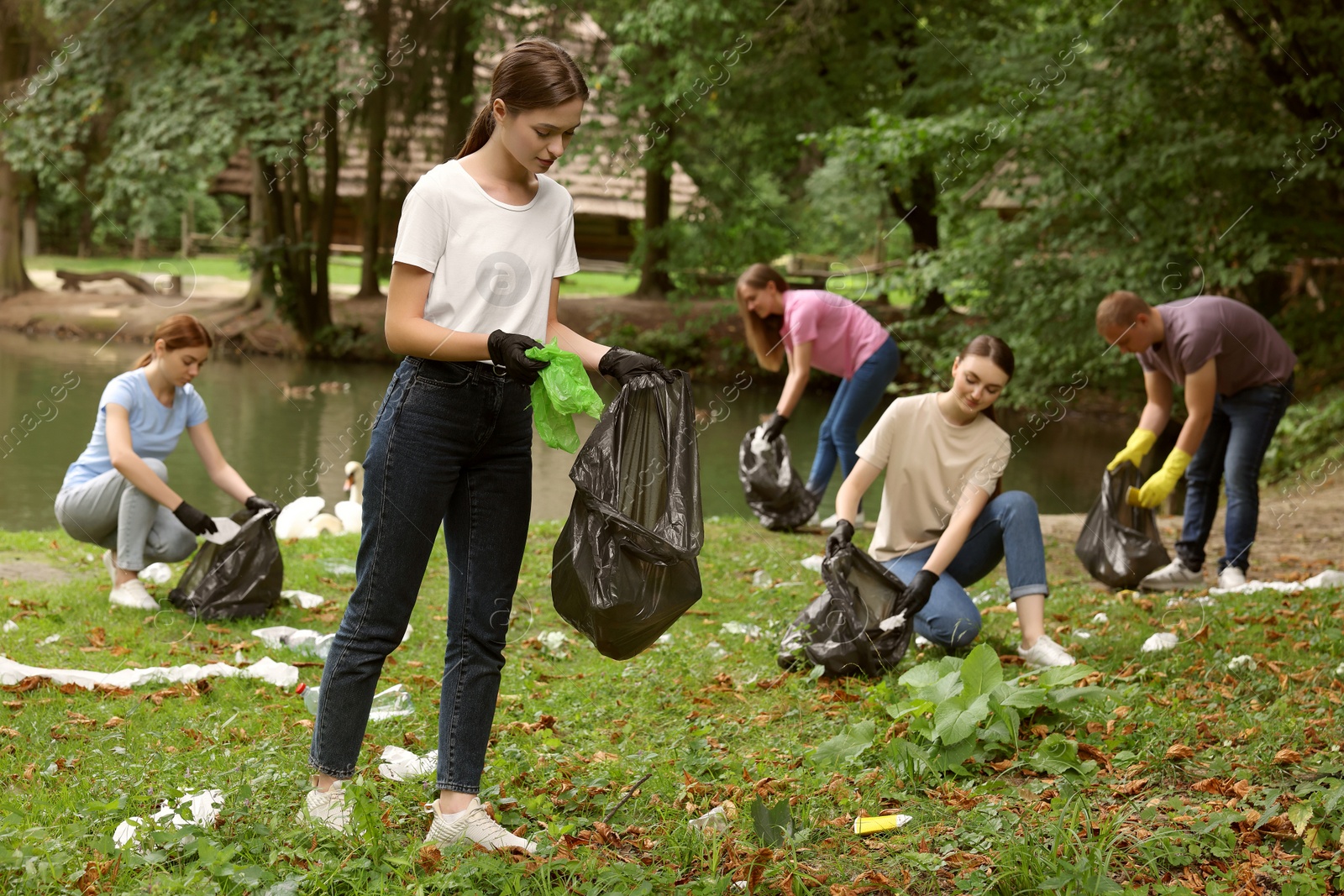 Photo of Group of people with plastic bags collecting garbage in park