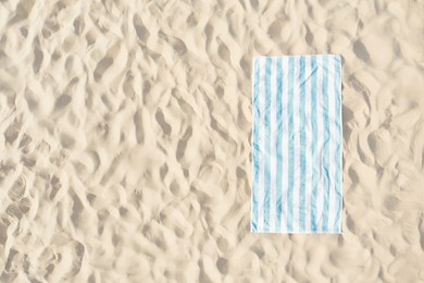 Image of Striped beach towel on sand, aerial view. Space for text