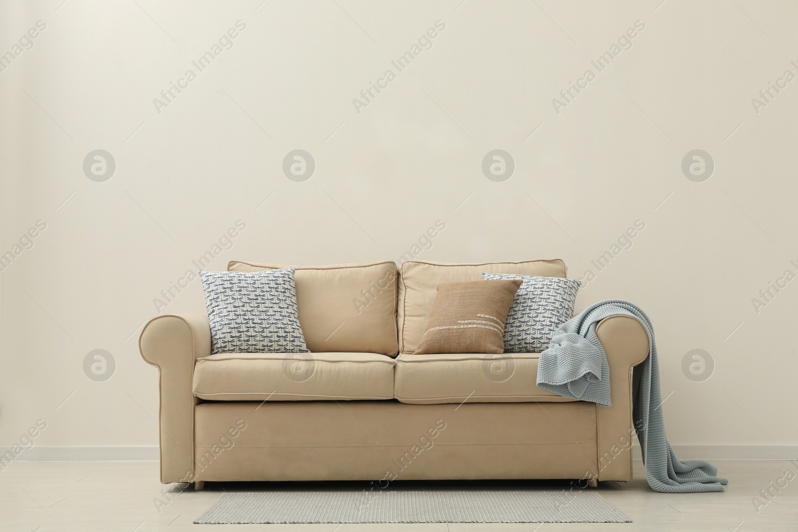 Photo of Comfortable sofa near beige wall in living room interior. Space for text