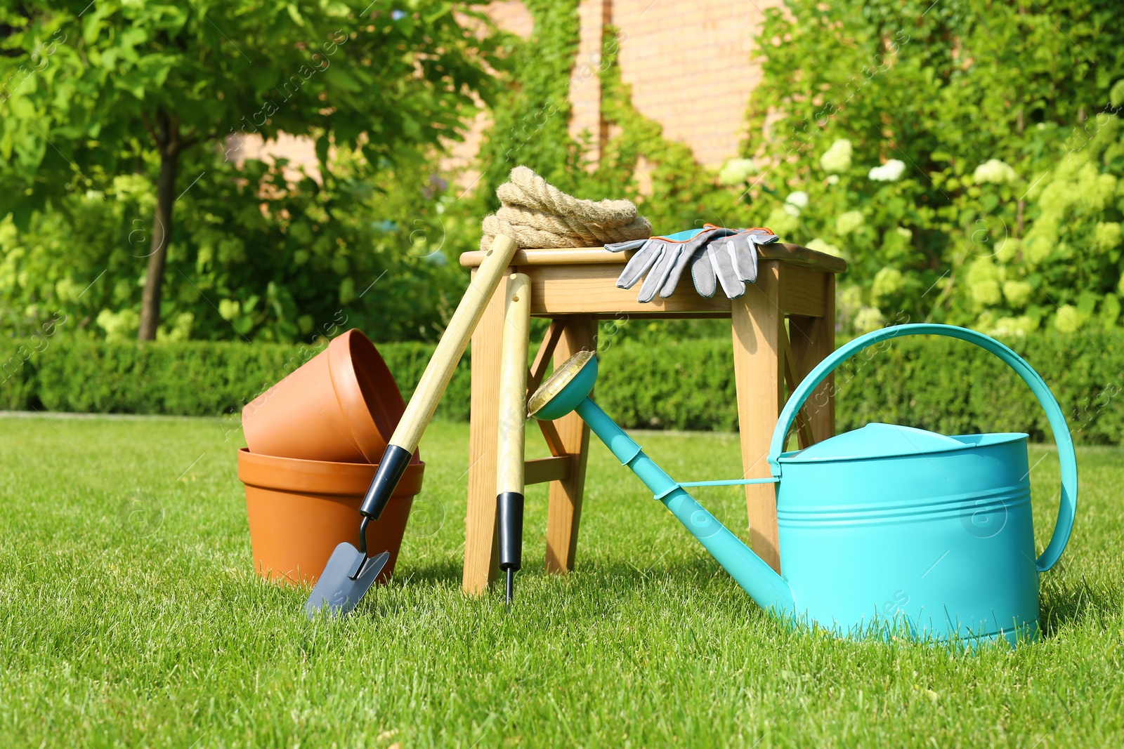 Photo of Set of gardening tools and stool on green grass