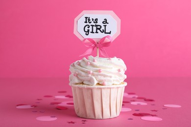 Photo of Beautifully decorated baby shower cupcake for girl with cream and topper on pink background