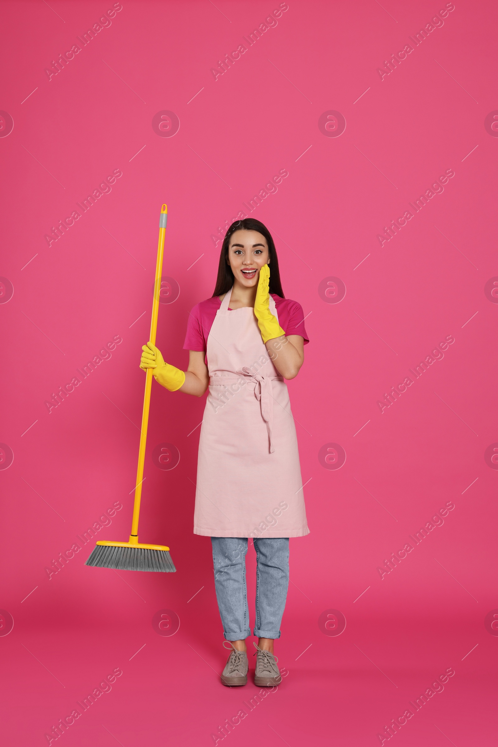 Photo of Beautiful young woman with broom on pink background