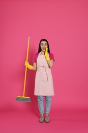 Beautiful young woman with broom on pink background