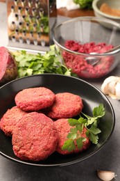Delicious beetroot cutlets and parsley in black bowl on table. Vegan dish