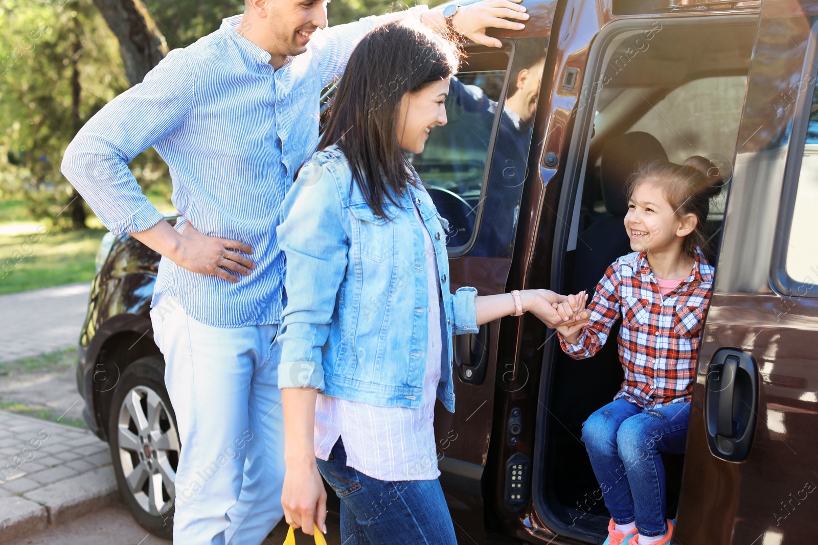 Photo of Young parents taking their little child to school by car