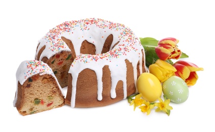 Photo of Glazed Easter cake with sprinkles, painted eggs and flowers on white background