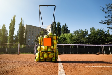 Photo of Basket with tennis balls on clay court