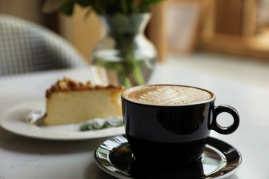 Cup of fresh coffee and dessert on table indoors