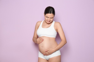 Photo of Beautiful pregnant woman holding belly on color background