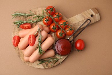 Delicious boiled sausages, tomato sauce, tomatoes and rosemary on beige table, top view