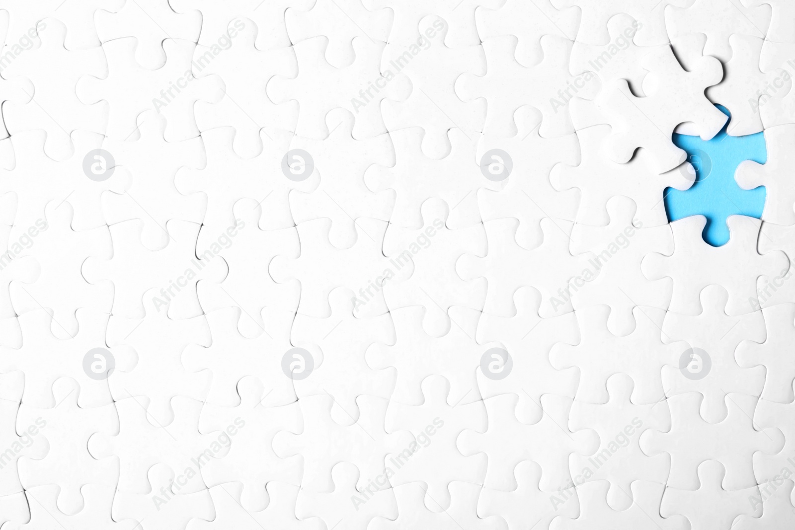 Photo of Blank white puzzle with separated piece on light blue background, top view. Space for text