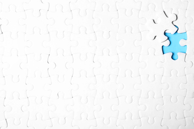 Photo of Blank white puzzle with separated piece on light blue background, top view. Space for text