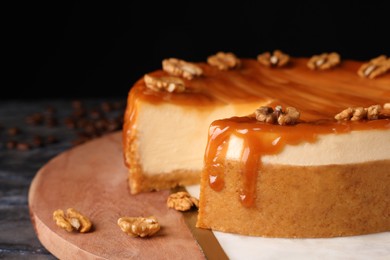 Sliced delicious cheesecake with caramel and walnuts on board, closeup