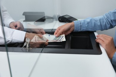 Photo of Woman giving money to cashier in bank, closeup. Currency exchange