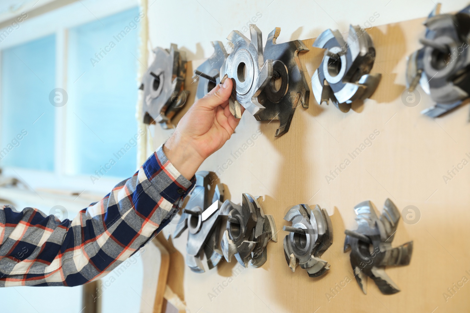 Photo of Working man choosing blade for circular saw at carpentry shop, closeup