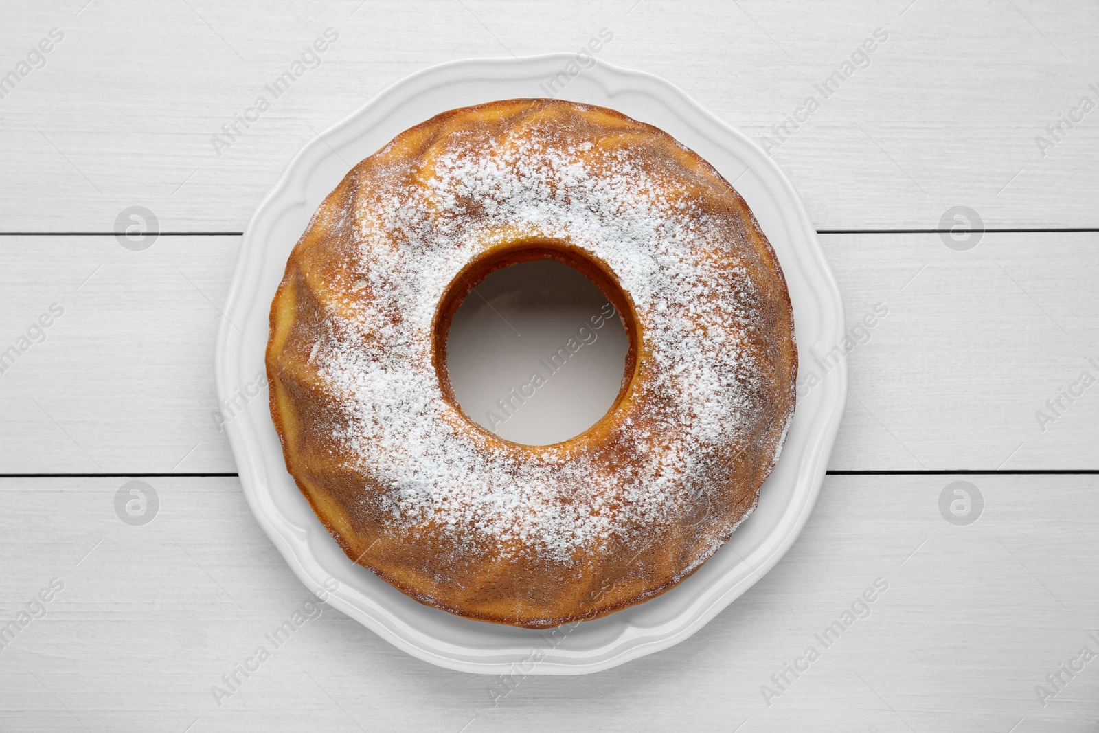 Photo of Homemade yogurt cake with powdered sugar on white wooden table, top view