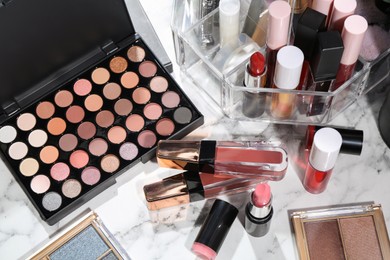 Photo of Bright lip glosses among different cosmetic products on white dressing table