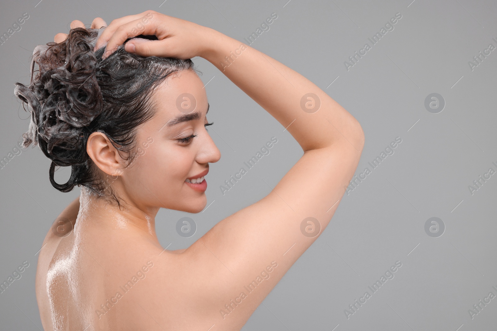 Photo of Beautiful woman washing hair on grey background. Space for text