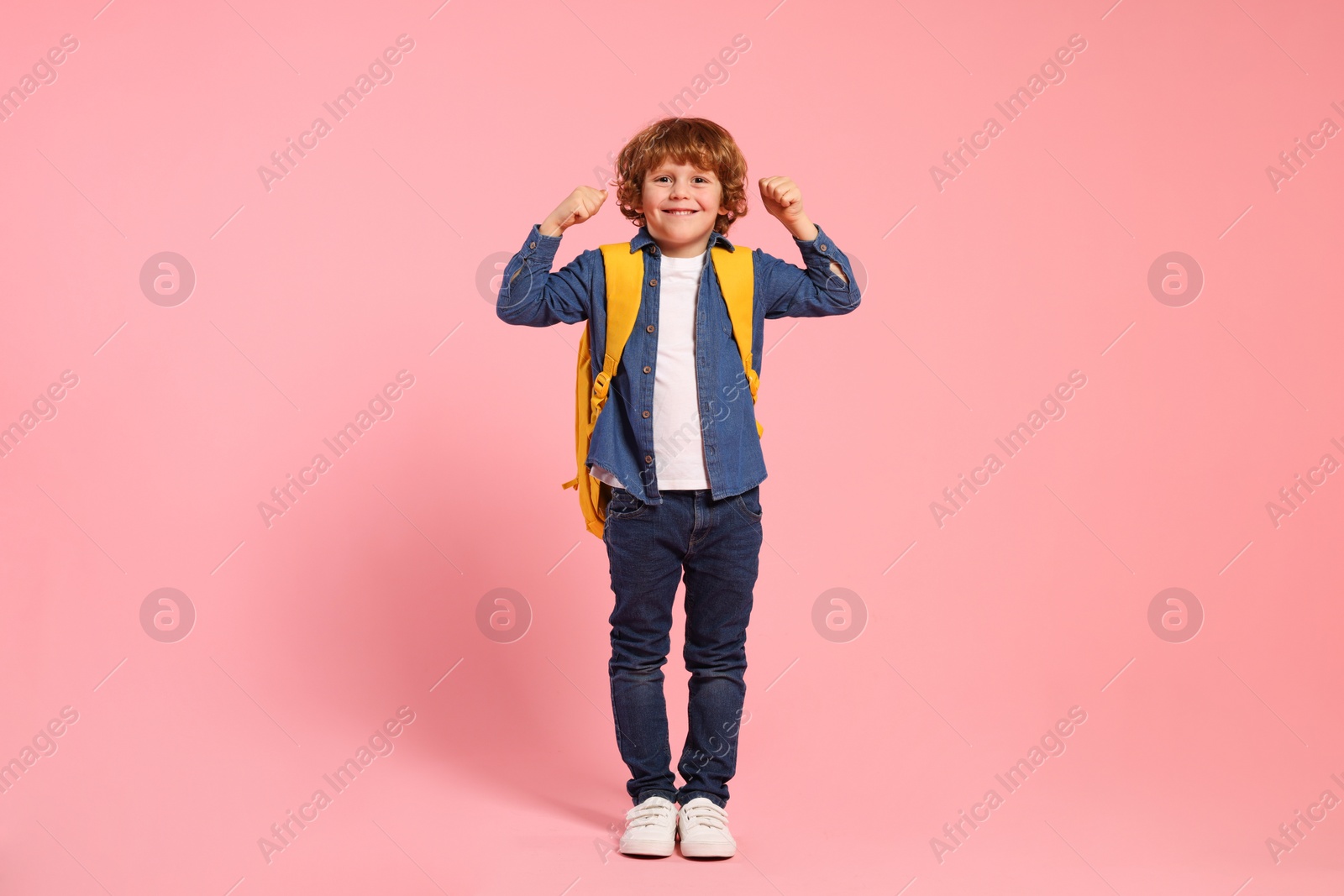 Photo of Happy schoolboy with backpack on pink background