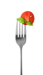 Fork with half of cherry tomato and basil isolated on white