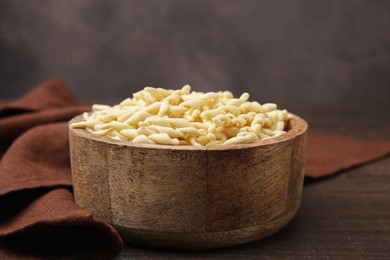 Uncooked trofie pasta in bowl on wooden table, closeup