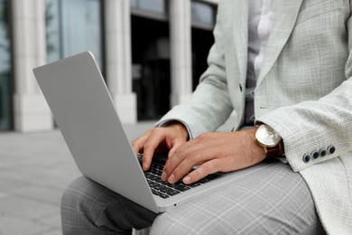 Photo of Businessman with laptop on city street, closeup