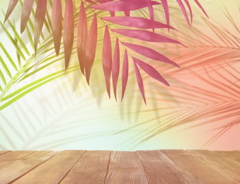 Palm branches and wooden table against light background, color tone effect. Summer party