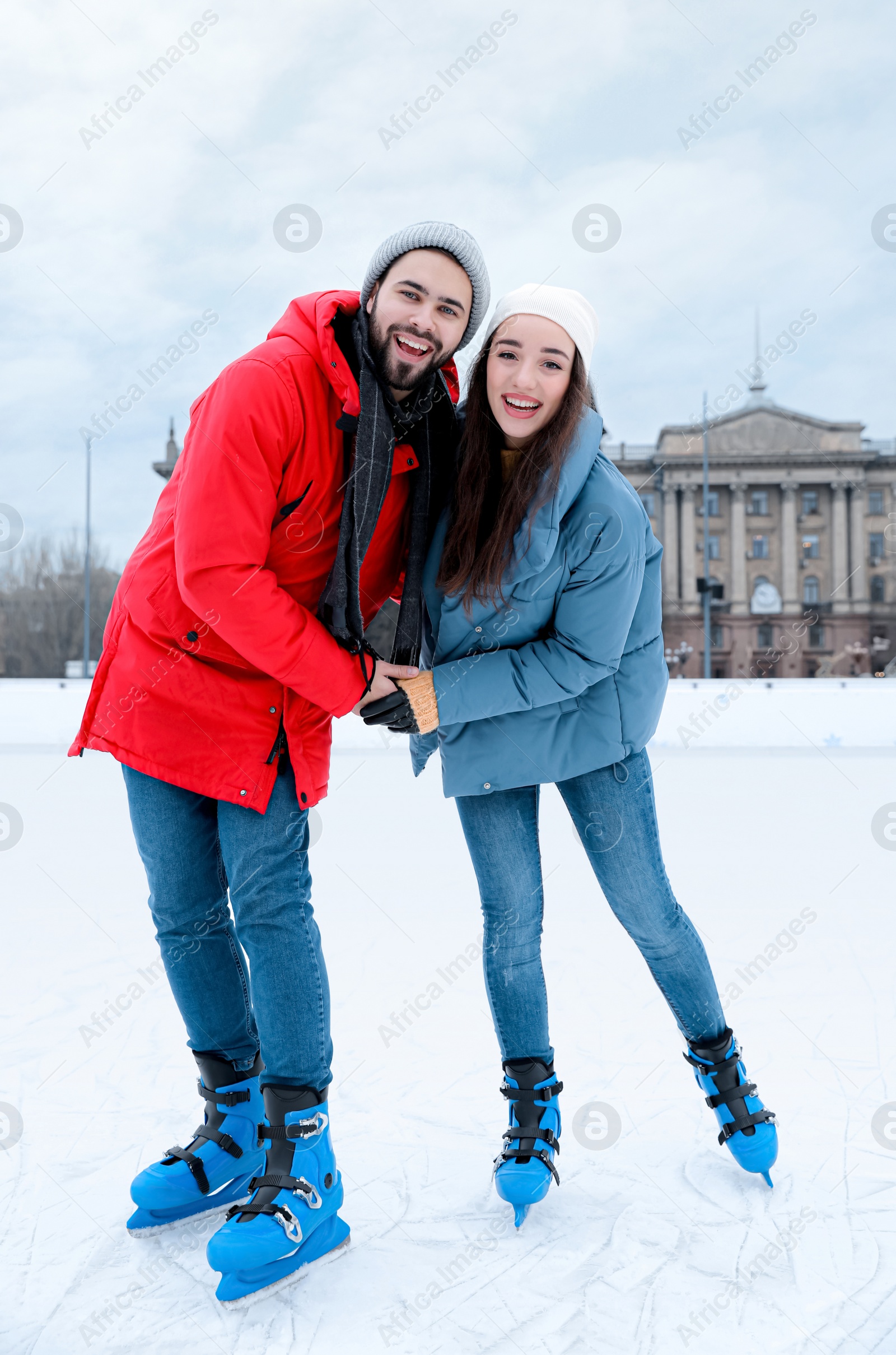 Image of Happy couple skating along ice rink outdoors