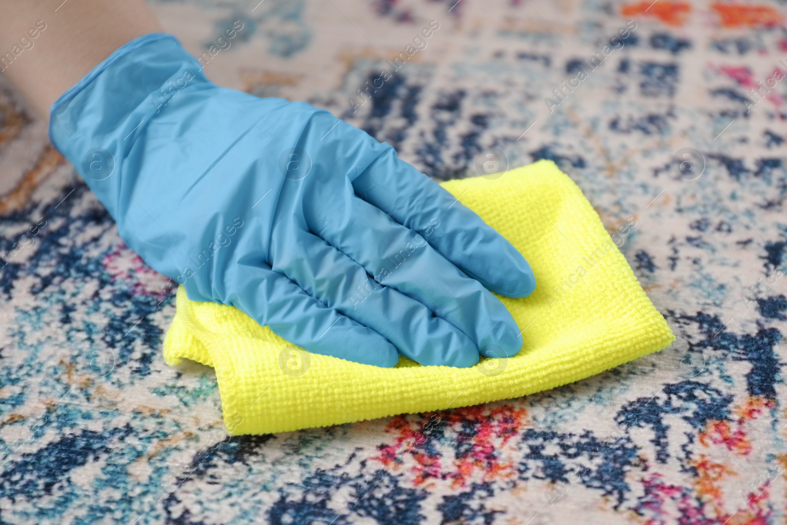 Photo of Woman in rubber gloves cleaning carpet with rag, closeup