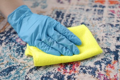 Woman in rubber gloves cleaning carpet with rag, closeup