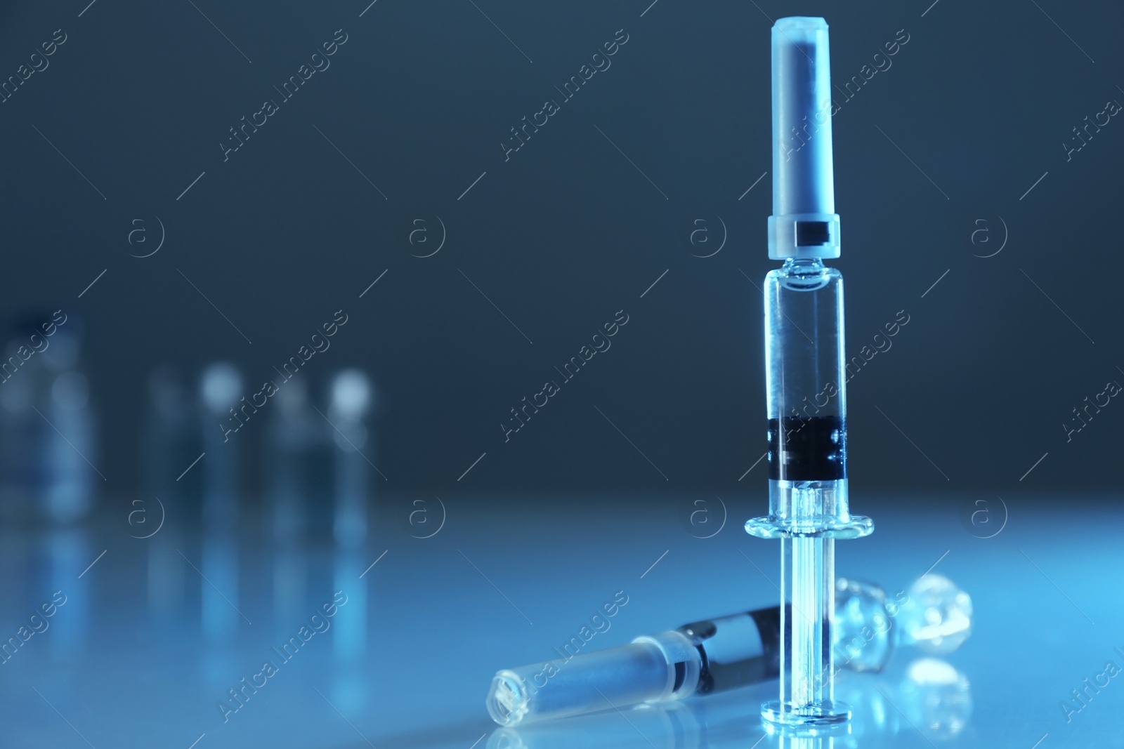 Photo of Syringes with COVID-19 vaccine on table, space for text