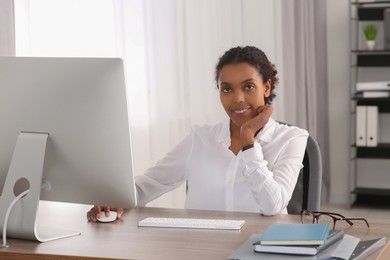 Smiling African American intern working with computer at table in office