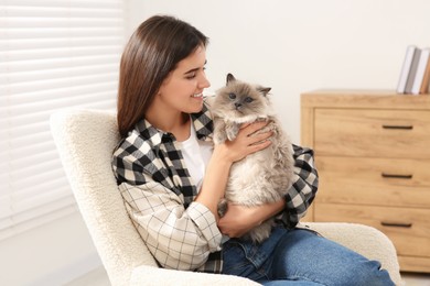 Photo of Woman with her cute cat on soft armchair at home