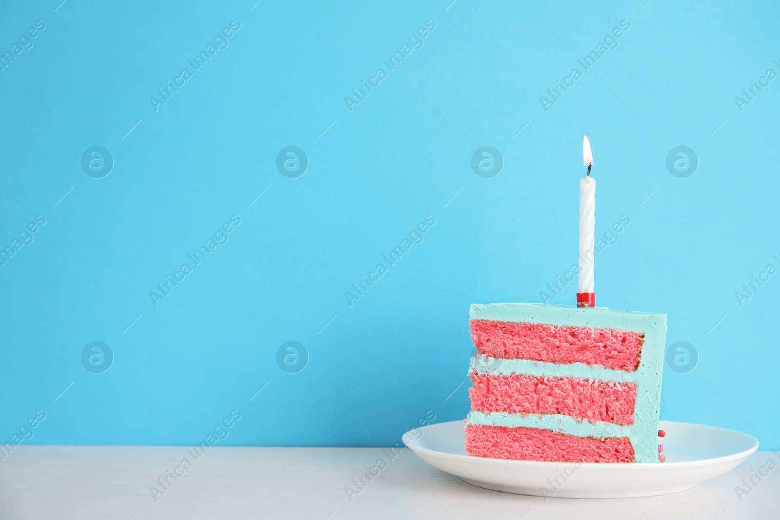 Photo of Slice of fresh delicious birthday cake with candle on table against color background. Space for text