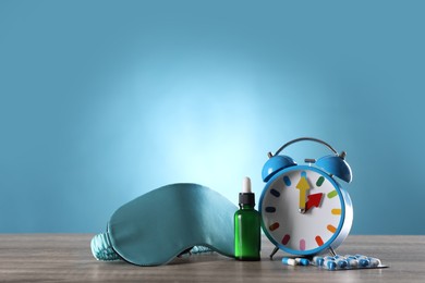 Photo of Sleeping mask, alarm clock and insomnia remedies on wooden table