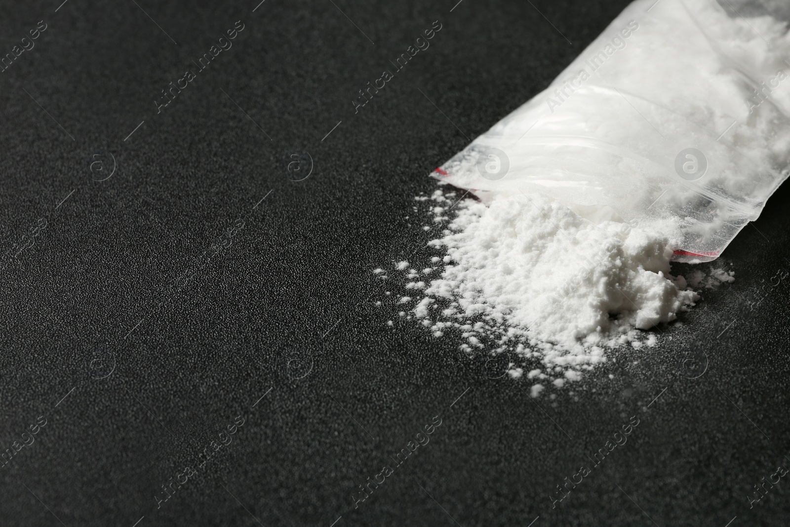 Photo of Cocaine in plastic bag on dark background, closeup. Space for text