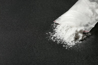 Photo of Cocaine in plastic bag on dark background, closeup. Space for text