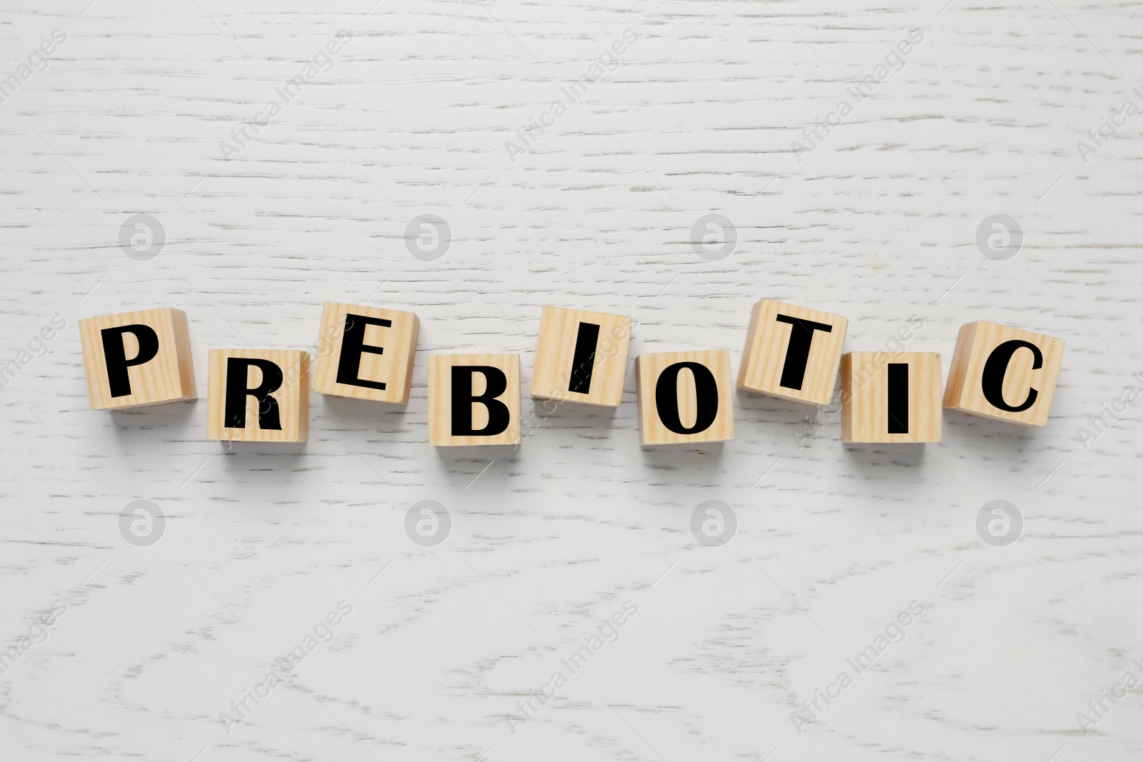 Photo of Wooden cubes with word Prebiotic on white table, flat lay