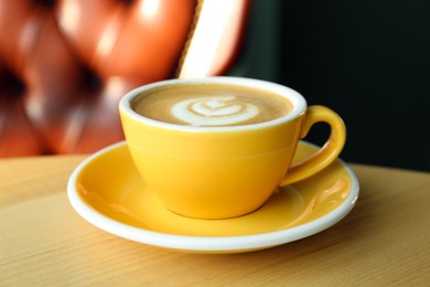Cup of delicious coffee on wooden table indoors, closeup