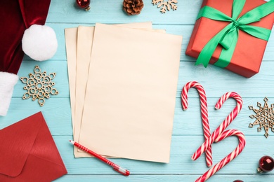 Photo of Flat lay composition with blank sheets of paper and Christmas decorations on light blue wooden table, space for text. Writing letter to Santa