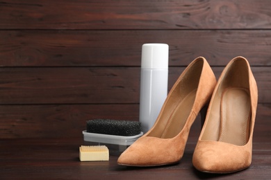 Photo of Stylish footwear with shoe care accessories on brown wooden table. Space for text