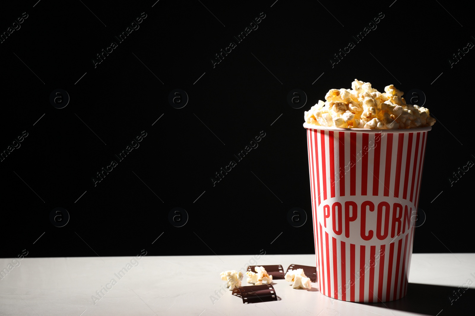 Photo of Delicious popcorn and tape on table. Space for text
