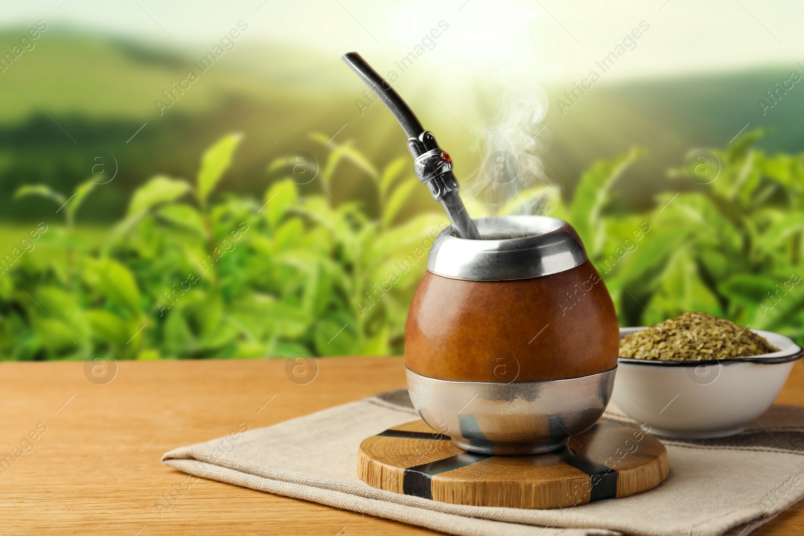 Image of Calabash with mate tea and bombilla on wooden table outdoors. Space for text