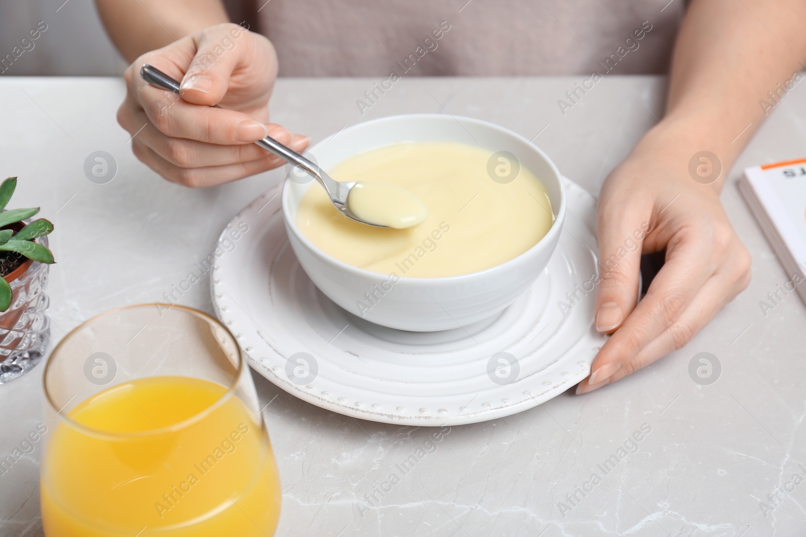 Photo of Woman with vanilla pudding at table, closeup